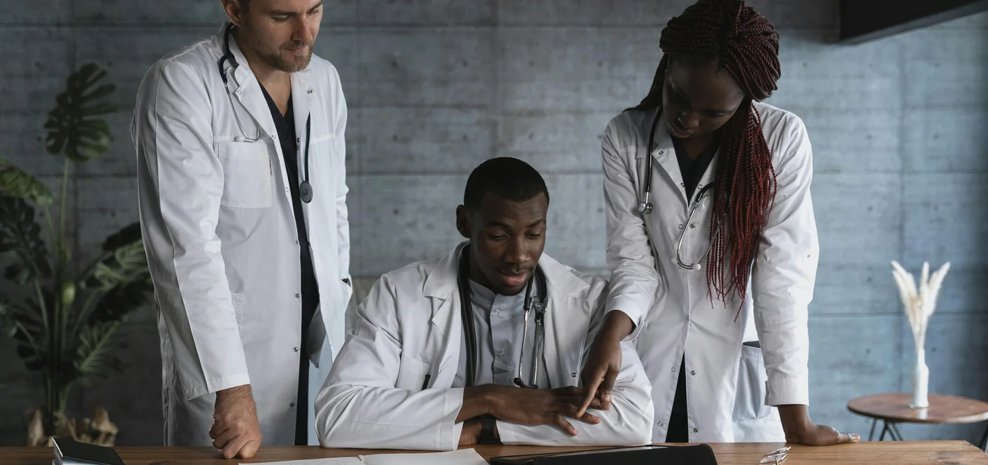 Three medical professionals collaborating around a desk during a clinical session